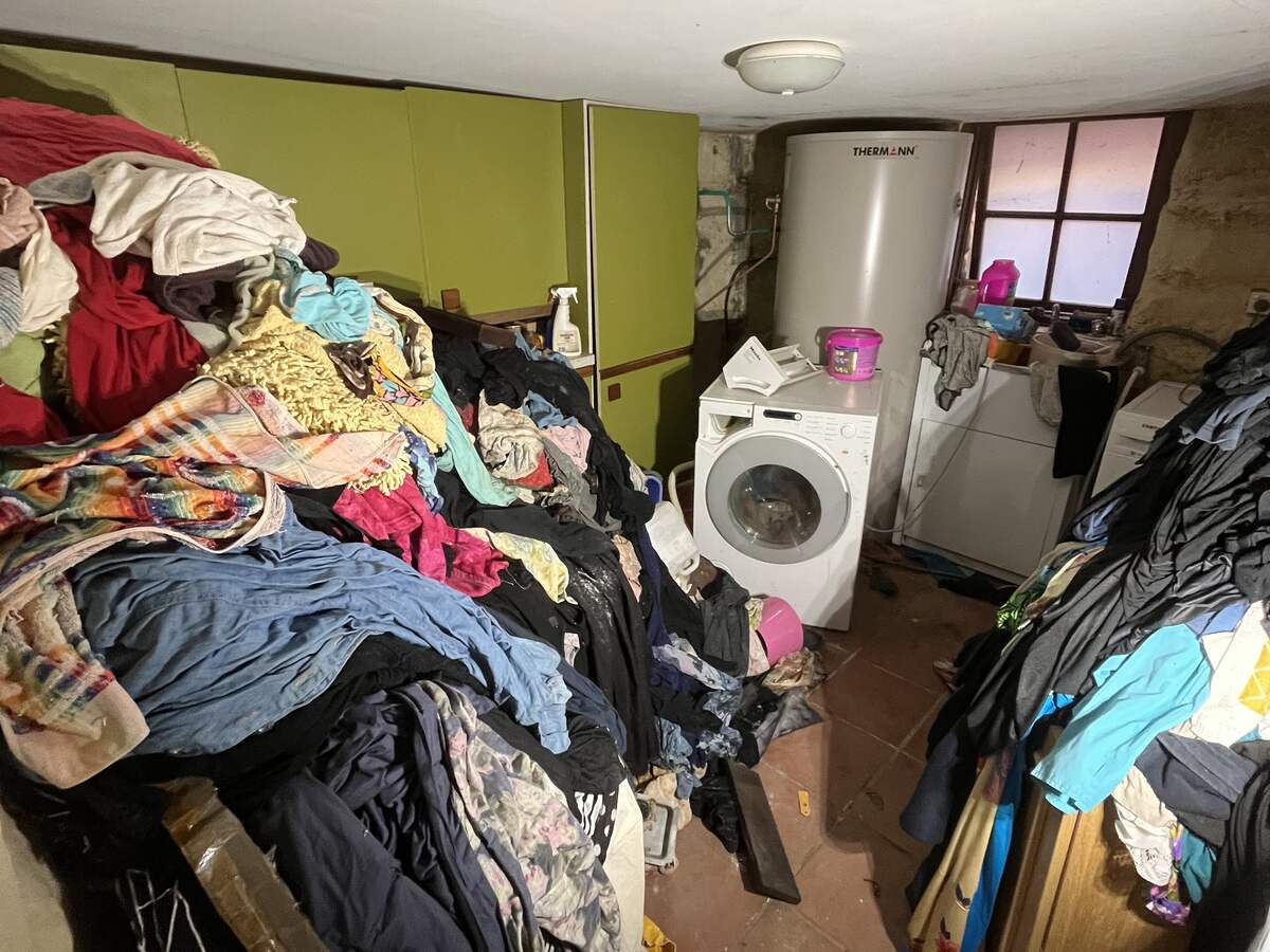 A basement laundry piled high with clothes before a clean up